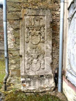 Hermannstein-Langhaus im Nordwesten am Kirchturm-Grabstein aus dem aufgelassenen Kirchhof mit Umschrift und ornamentierten Wappenkartuschen in halbplastischer Steinmetzarbeit
