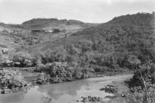 Flusslandschaft und Hügel : Im Vordergrund ein Flusslauf mit baumbewachsenen Inseln, dahinter Hügel mit Grasflächen und Baumgruppen. Auf dem Hang mehrere Gebäude.