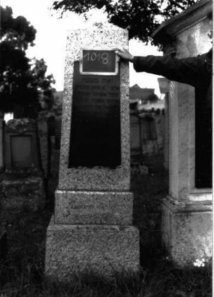 Grabstein 1018 (Index: 100104000) Material: Granit Zustand: gut erhalten Maße HxBxT: 178x47x20 cm Beschreibung: obeliskenartige Stele auf getrepptem Sockel, eingelassene hochrechteckige Schrifttafel: Grabstein 1018