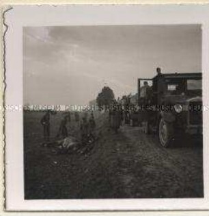 Soldaten mit totem Pferd am Wegesrand