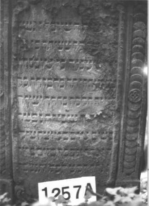 Grabstein 1257 (Index: 99900073) Material: Sandstein Zustand: stark verwittert Maße HxBxT: 125x69x13 cm Beschreibung: Stele mit Kielbogenabschluss, im Bogenfeld Akanthusornamente, seitlicher Rahmen mit Schuppenfries Symbolik: Akanthus, Schuppenfries: Grabstein 1257A