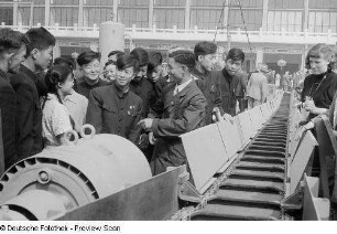 Besucher der Leipziger Herbstmesse 1954 wohnen der Vorführung eines Förderbandes der chinesischen Sektion bei
