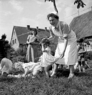 Glauburg-Glauberg (Wetteraukreis). Kinderheim? Kinder mit ihrer Erzieherin (Frau Hille?) im Garten beim Spielen
