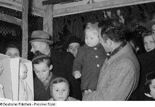 Verkaufsstand für Puppen und Spielwaren umringt von Besuchern auf dem Leipziger Weihnachtsmarkt bei Dunkelheit