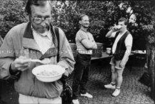 Franziskaner Kloster Pankow, Suppenküche, Mittagessen - zwei Männer an Getränke versorgung, einer mit Suppenteller