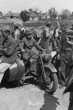 Zweiter Weltkrieg. Zur Einquartierung. Sowjetunion. Wehrmachtsangehörige neben einem Motorradfahrer in einem Dorf