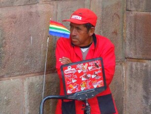 Cusco - Eisverkäufer mit Regenbogenfahne : Ein Eisverkäufer steht vor einer in der Inka-Zeit erbauten Mauer. Aufgenommen am 31. August 2011 in Cusco