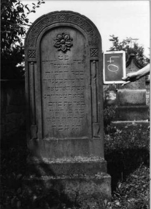 Grabstein 40 (Index: 99801862) Material: Sandstein Zustand: gut Maße HxBxT: 158x60x18 cm Beschreibung: Stele, getreppter Sockel, Rundbogen Symbolik: nach unten zeiogende Fackeln, Blüte, eingemeißelte Ornamentik mit Rundbogen Besonderheit: kulturhistorisch wertvoll / künstl.-formale Gründe (Ornamentik): Grabstein 40