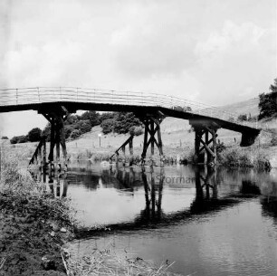 Klein Barnitz: Trave: Holzbrücke für Fußgänger: hinten Wiesen mit Zaun und Bäume