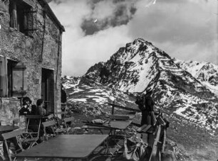 An der Hütte : Szene an der Berghütte auf dem Schafberg an der einige Bergsteiger pausieren. Im Hintergrund ist der Piz Murargl sichtbar.