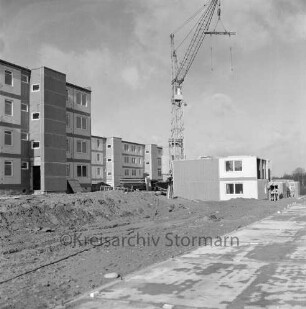 Lottbek: Neubausiedlung: Wohnungsbau: vorn Fundament: links Erdhaufen und Reste von Baumaterial: dahinter Wohnblocks vor Fertigstellung: in der Mitte Baukran: links davor Wohnblock im Bau
