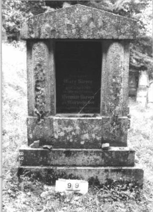 Grabstein 99 (Index: 99800116) Material: Granit, Schriftplatte polierter Granit Zustand: Platte gesprungen Maße HxBxT: 196x119x29 cm Beschreibung: ädikulaartige Stele, Giebelabschluß, Halbsäulen, eingelassene rechteckige Schriftplatte, getreppter Sockel Besonderheit: Doppelgrab für Eheleute: Grabstein 99