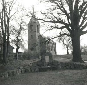 Mochow. Dorfkirche (1880). Ansicht von Südwesten mit Denkmal für die Gefallenen beider Weltkriege und mächtiger Eiche