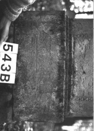 Grabstein 543 (Index: 99900810) Material: Sandstein Zustand: stark verwittert Maße HxBxT: 155x60x25 cm Beschreibung: aufgesockelte Stele mit Dreiecksabschluss, darauf Giebel- und Eckakroterien, unterhalb der Verdachung Zinnenfries, Schriftfeld umgeben von Diamantfries und Rosetten Symbolik: Zinnenfries, Diamantfries, Rosetten: Grabstein 543B