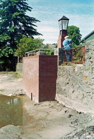 Fritz-Berodt-Straße 7-9: Hofanlage: Teich bei Niedrigwasser: Ufermauer mit Fundamenten, Wasserzulauf nach Sanierung: an Geländer Mann, Laterne auf Pfeiler
