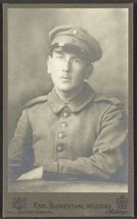 Hermann Uhl, in Uniform, sitzend, ein Arm auf einem Tisch vor ihm aufgelegt