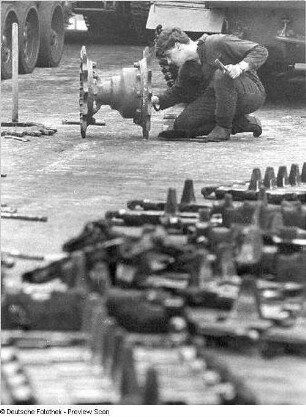 Goldberg (Kreis Lübz). Nationale Volksarmee - Landstreitkräfte. Panzerregiment 8 (PR-8). Freifläche vor Panzerhallen. Soldat bei Instandsetzungs- bzw. Wartungsarbeiten an Gleisketten für Kampfpanzer T-54