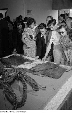 Besucher der Leipziger Herbstmesse 1954 begutachten Materialproben zur Seilherstellung
