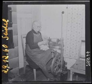 Frau aus dem Erzgebirge während der Arbeit am Spinnrad : Frau am Spinnrad, Erzgeb., 1960