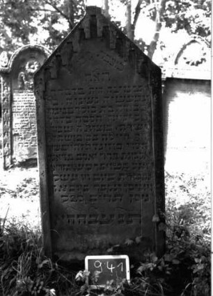 Grabstein 941 (Index: 100103837) Material: Sandstein Zustand: gut erhalten, an den Rändern beginnende Verwitterung Maße HxBxT: 158x71x12 cm Beschreibung: Stele, Dreiecksabschluss mit rechteckigem Giebelakroter, Schriftfeld eingetieft mit Zinnenfries Symbolik: Zinnenfries: Grabstein 941
