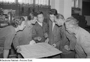 Mehrere Personen studieren eine technische Zeichnung beim Aufbau des chinesischen Pavillons für die Herbstmesse 1953