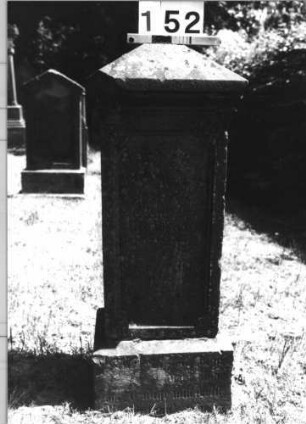 Grabstein 152 (Index: 100085445) Maße HxBxT: 107x40x29 cm Beschreibung: Stele, Sockel, Giebel, rechteckiges Schriftfeld eingetieft auf Vorderseite: Grabstein 152