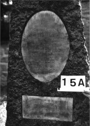 Grabstein 15 (Index: 100081771) Material: Granit, weiße Marmorplatten Zustand: gut Maße HxBxT: 166x52x31 cm Beschreibung: konische Stele, flacher Segmentbogenabschl. , ovale u. querrechteckige Schriftplatte: Grabstein 15A