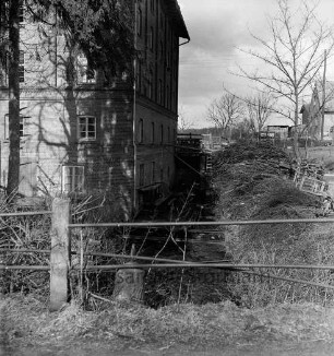 Hoherdammer Mühle: Rentnerwohnheim der Gemeinde: Durchlauf der Norderbeste: vorn Brückengeländer: links Tanne: vorn rechts an Böschung Strauchwerk: dahinter Baum und Wohnhäuser