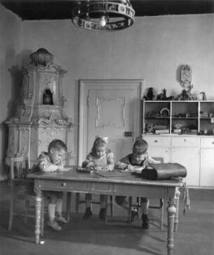 Kinderbilder. Steiermark. Drei Kinder bei den Hausaufgaben im Raum eines Schlosses?