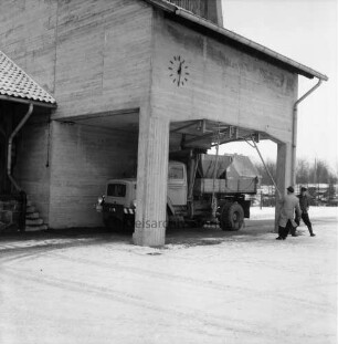 A 1: Bad Oldesloe / Rethwischfeld: Autobahnmeisterei: Betonsilo für Streugut, an Fassade Wanduhr: automatischer Streu-Lkw wird beladen: Mann beim Schließen der Ladeluke: im Winter
