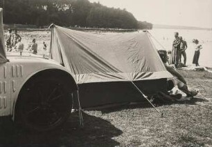 Wochenende an einem See. Am Ufer ein Zelt, ein Auto und Badende