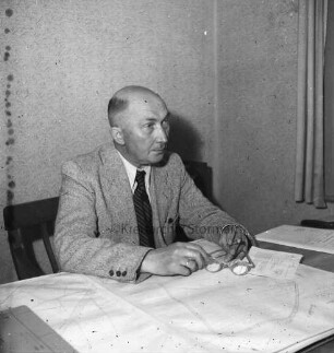 Rosch, Willy: geboren 12. April 1890: bis 1955 Leiter des Katasteramtes in Bad Oldesloe; 1950 bis 1962 Bürgerworthalter von Bad Oldesloe: Einwohner von Bad Oldesloe: in Büro, am Schreibtisch: in Händen Brille, Zigarre