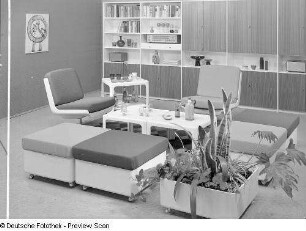 Blumenkasten : Möbelprogramm "variopur" (1973; VEB Petrolchemisches Kombinat Schwedt). Vier Hocker und zwei Drehstühle mit zwei Beistelltischen, Barwagen und Blumenkasten vor Anbauwand