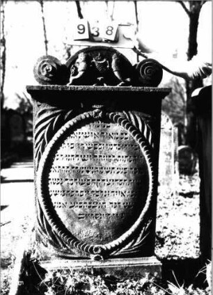 Grabstein 938 (Index: 99753171) Material: Sandstein Zustand: gut Maße HxBxT: 135x75x30 cm Beschreibung: Stele, profilierter Sockel, Abdeckplatte mit Volutenaufsatz Symbolik: Löwenpaar herschauend, Kanne zwischen sich, Blätter, Blüten, Scheibenfries, Voluten: Grabstein 938