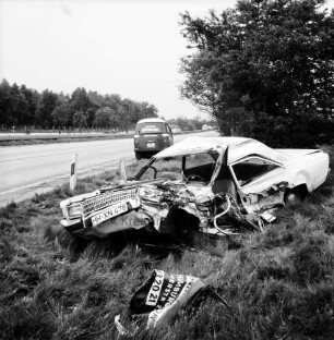 A 1: Verkehrsunfall: Zusammenstoß von Pkw und Lieferwagen: Wrack von Unfall-Pkw neben Straße, vorne Trümmerteil: dahinter auf Seitenstreifen Unfall-Lieferwagen: Leitpfosten: hinten Mittelstreifen, Autos auf Gegenfahrbahn: Büsche, Bäume