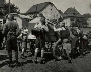 Der Zirkus kommt. Unbezähmbare Neugier der Jungen. Sie schauen sich alles an - selbst das Wageninnere eines kleinen Transportwagens