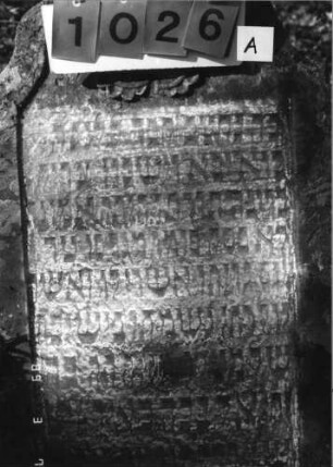 Grabstein 1026 (Index: 99751285) Material: Sandstein Zustand: stark verwittert Maße HxBxT: 120x66x8 cm Beschreibung: Stele, geschwungener Abschluß, Schriftfeld eingetieft Symbolik: Medaillon: Grabstein 1026A