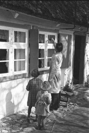 Althagen: Maler streicht Fenster, zwei Kinder dabei