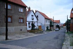 Dorfstraße mit Häusern, gepflasterter Rinnstein