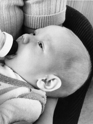 Ein Baby wird gefüttert. Es erhält sein Fläschchen.