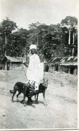 Afrikanische Frau mit zwei angeleinten Hunden im Dorf Molundu