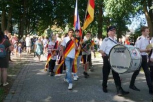 Bad Oldesloe: Kindervogelschießen: Einlauf des Festumzuges auf den Festplatz (Exer) über Konrad-Adenauer-Ring, mittig Fahnenträger und Kronengruppe, links und rechts Passanten, 30.06.2022