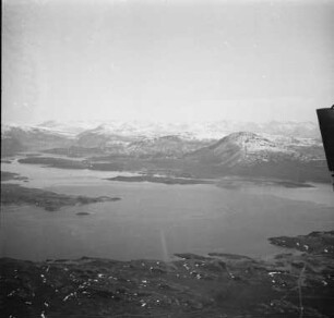 Luftbildaufnahme der Küstenlandschaft : Fjord am Fuß eines Felsmassivs an der norwegischen Küste.