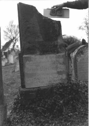 Grabstein 83 (Index: 99786728) Zustand: obere Hälfte abgebrochen Maße HxBxT: 150x70x18 cm Besonderheit: kulturhistorisch wertvoll / hist.-wiss. Gründe (Gemeindestellung): Grabstein 83