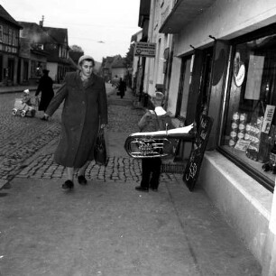 Gedern. Junge mit seiner Tuba auf dem Gehweg vor einem Lebensmittelladen