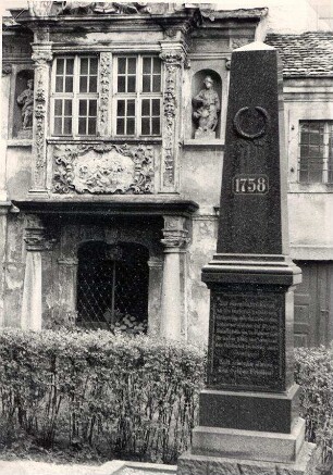 Denkmal zur Erinnerung an die Schlacht bei Hochkirch 1758, dahinter altes Portal : Pomjatna stela za bitwu pola Bukec 1758