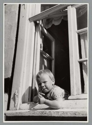 Kind aus einem offenen Fenster blickend
