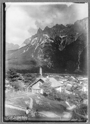 Vor Mittenwald, darüber das Karwendelgebirge : Ortsteilansicht mit barocker Pfarrkirche gegen das Karwendelgebirge