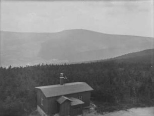 Landschaftsblick : Blick über eine hügelige Landschaft. Vorn eine Wetterstation, dahinter Wald und im Hintergrund ein Höhenzug
