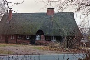 Nütschau: Schloßstraße 42a-c: traufständige Mehrfamilienkate aus Fachwerk mit Reetdach: Straßenfront: Eingangstüren, Sprossenfenster, Heuluke, links Backsteinanbau